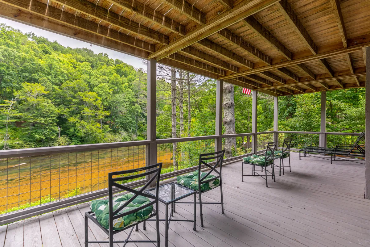 A peaceful wooden deck overlooks the tranquil river, surrounded by lush green foliage. Outdoor seating provides a relaxing place to enjoy the views, with the river just steps away, perfect for wildlife watching, stargazing, or sipping morning coffee.
