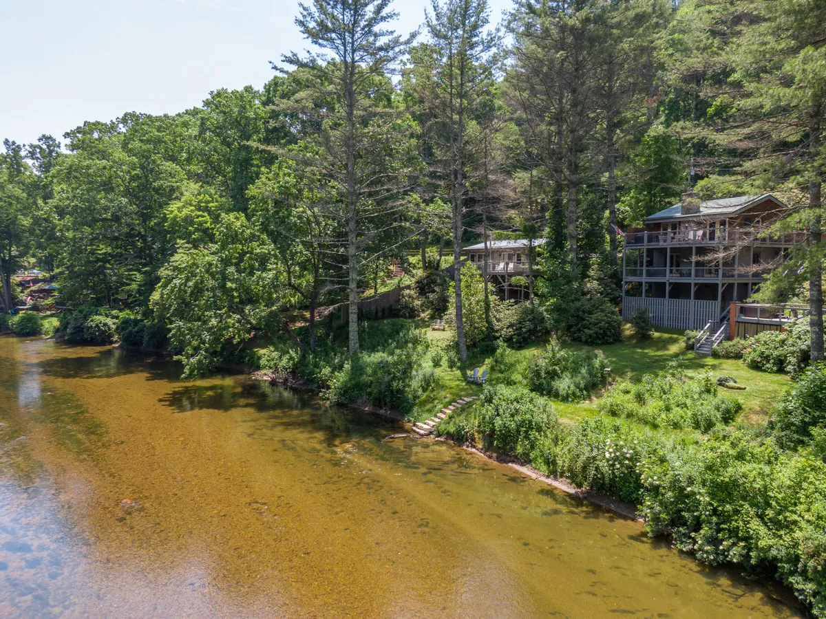 This image shows a tranquil riverside setting with clear water, lush greenery, and wooden structures. The area looks inviting for outdoor activities like fishing, boating, or simply unwinding by the water’s edge. The bright, vibrant landscape evokes the lively spirit of spring and summer.