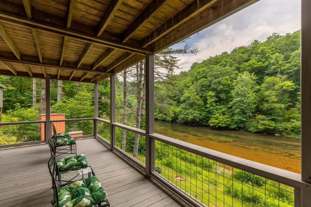 A wider perspective of the deck area, complete with rocking chairs that overlook the gently flowing river and lush greenery. The seating invites guests to relax, birdwatch, or enjoy riverside chats, perfectly matching the section’s emphasis on connecting with nature.