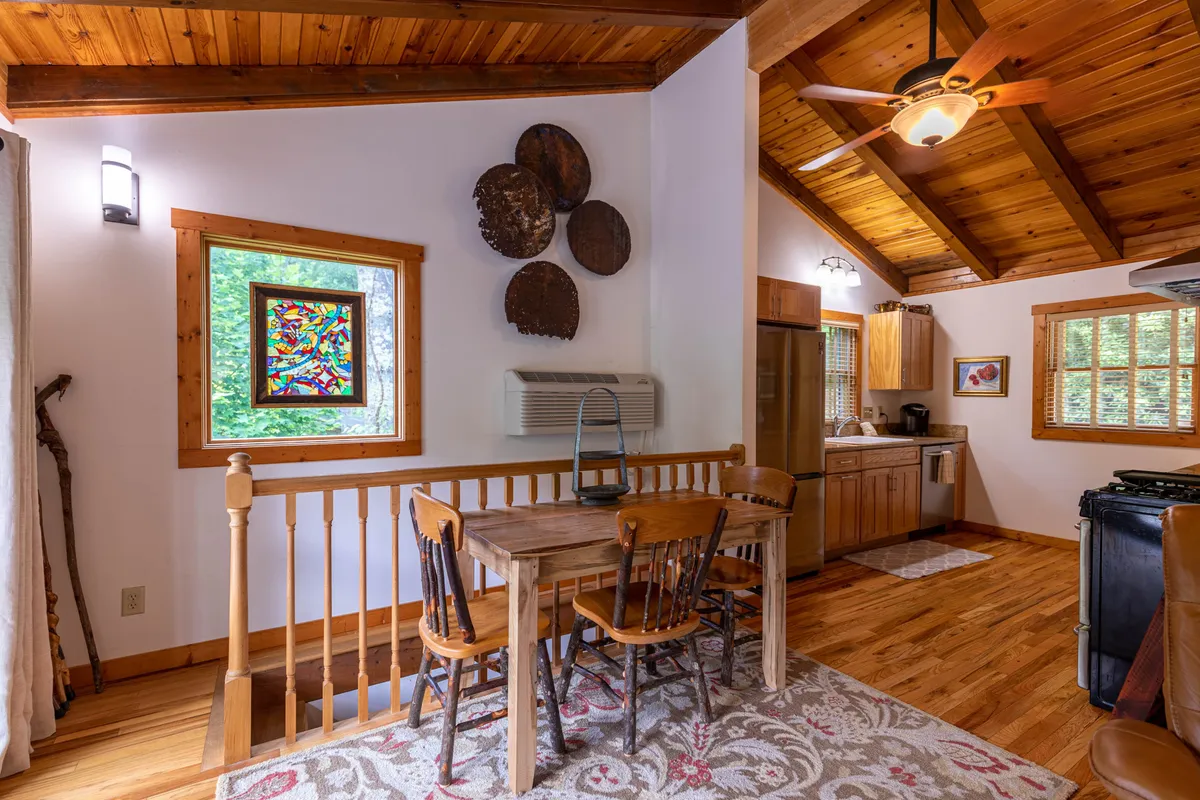 A warm dining area with a wooden table set beneath a stained glass window, flanked by cozy kitchen details and inviting wall décor. The layout encourages shared meals and conversation.